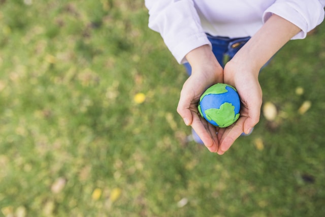 elevated-view-small-clay-globe-cupped-hands-grass